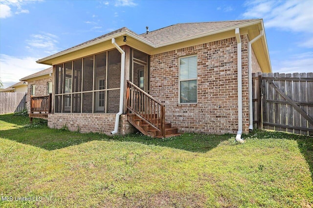 back of property featuring a lawn, brick siding, and a sunroom