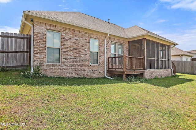 rear view of property with a lawn, fence, a sunroom, and brick siding