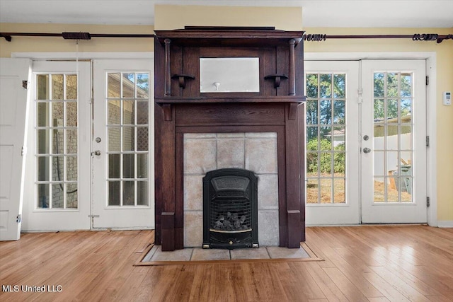 unfurnished living room with light wood-type flooring, french doors, and plenty of natural light