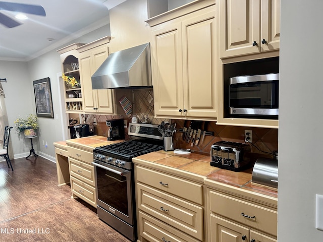 856 Wellington Way, Madison, MS 39110 - kitchen featuring appliances with stainless steel finishes, wall chimney range hood, cream cabinets, tile countertops, and ornamental molding