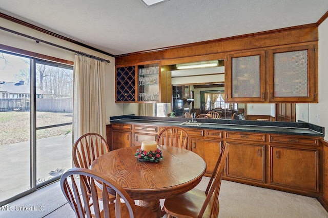 kitchen with a healthy amount of sunlight, glass insert cabinets, a textured ceiling, and light colored carpet