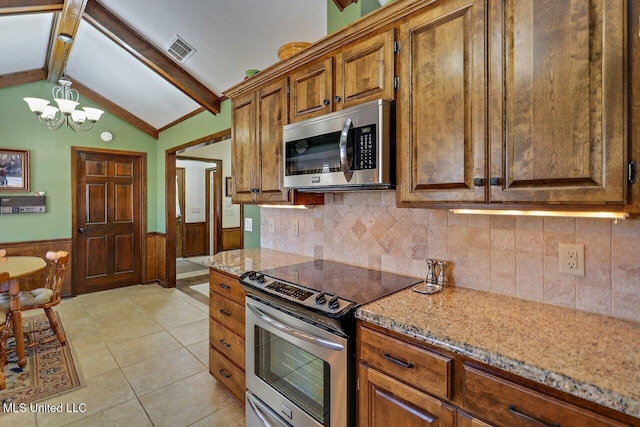 kitchen featuring vaulted ceiling with beams, a wainscoted wall, stainless steel appliances, visible vents, and brown cabinets