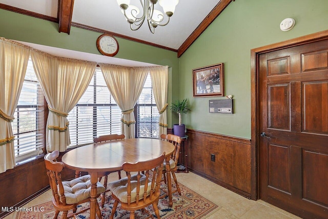 dining space with wooden walls, lofted ceiling with beams, a wainscoted wall, ornamental molding, and a notable chandelier