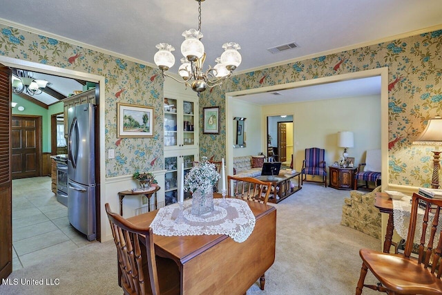 dining room with visible vents, a notable chandelier, light carpet, and wallpapered walls