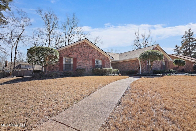 ranch-style house featuring brick siding, a front yard, and fence