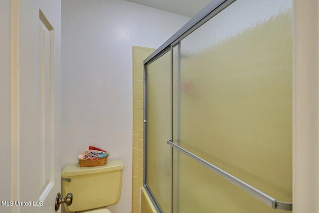 bathroom featuring combined bath / shower with glass door and toilet