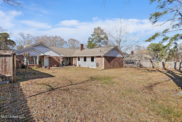 rear view of property with a chimney, fence, and brick siding