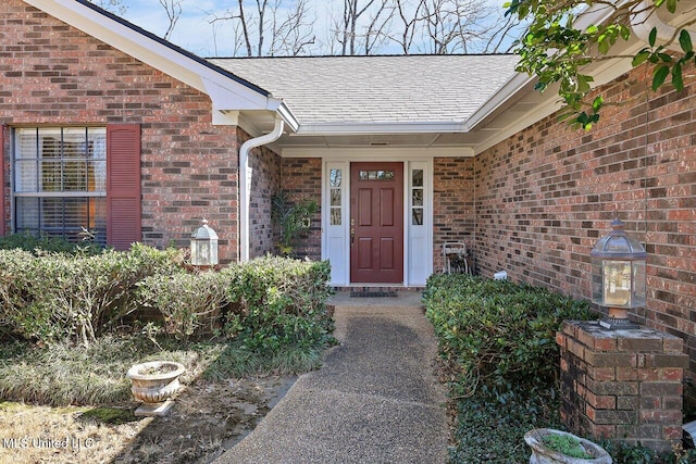 property entrance with roof with shingles and brick siding