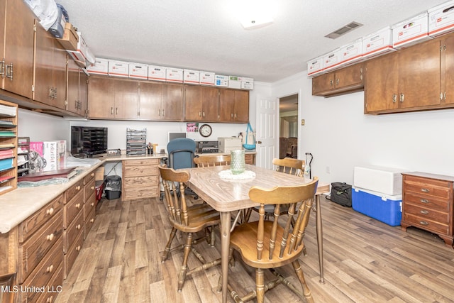 10001 Echo Glen Dr, Moss Point, MS 39562 - kitchen featuring light wood-type flooring, light countertops, ornamental molding, a textured ceiling, and brown cabinetry