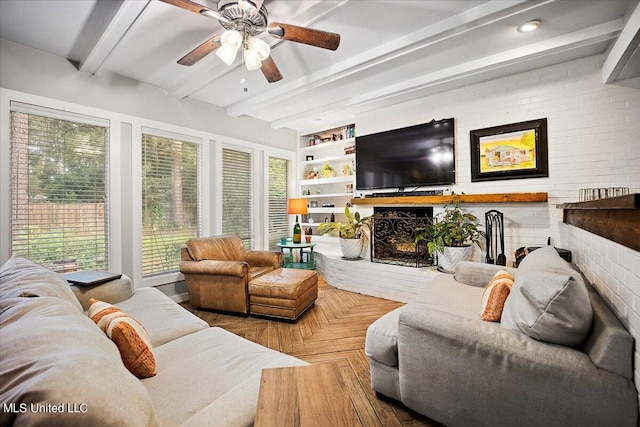 living room featuring beamed ceiling, parquet flooring, brick wall, a fireplace, and ceiling fan