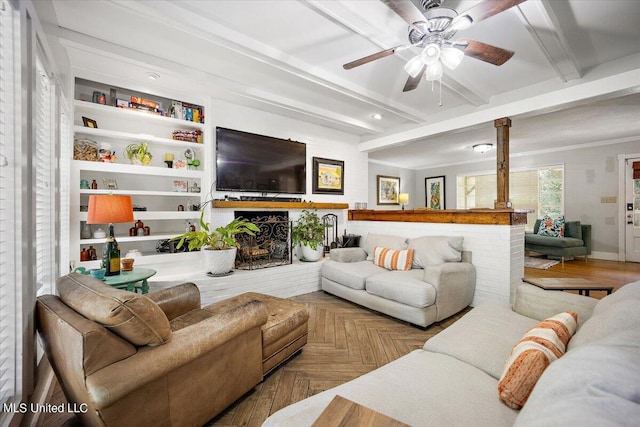 living room featuring beam ceiling, ceiling fan, ornamental molding, parquet floors, and built in shelves