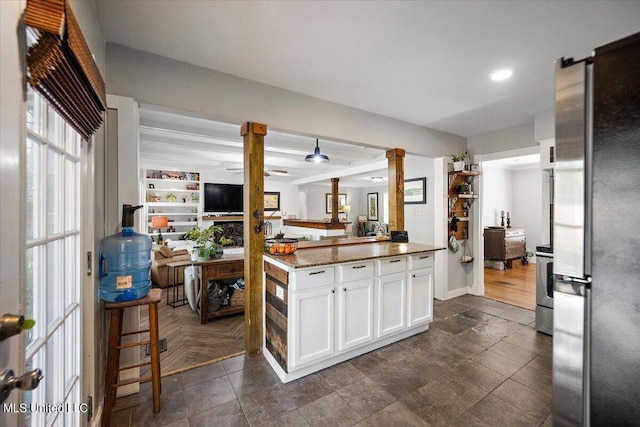 kitchen featuring freestanding refrigerator, white cabinets, stove, light stone counters, and recessed lighting