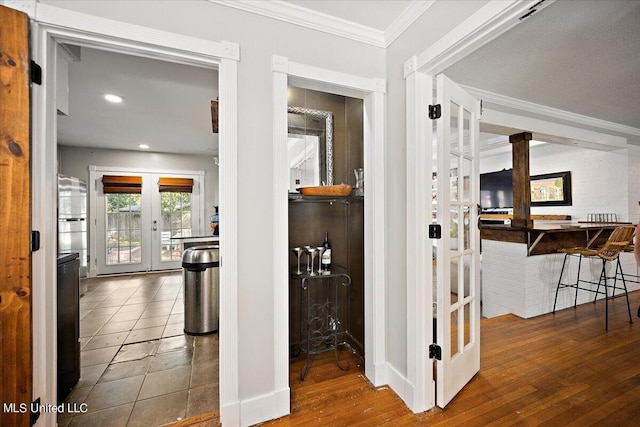 hallway with wood finished floors, french doors, ornate columns, ornamental molding, and recessed lighting