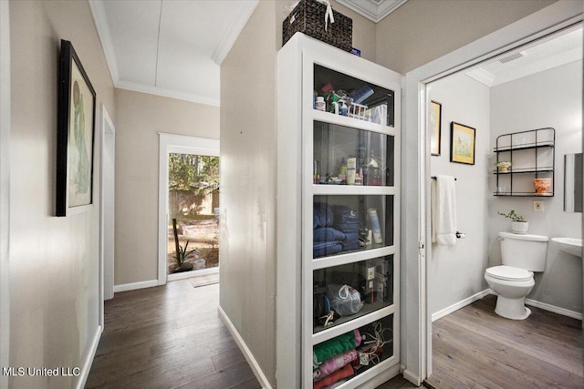 corridor featuring baseboards, ornamental molding, and wood finished floors