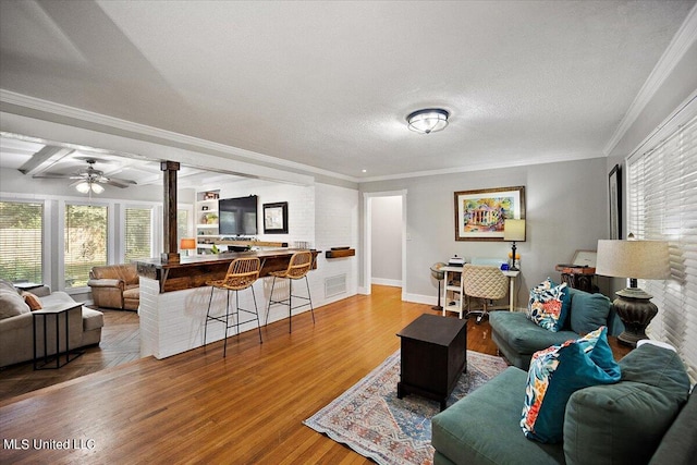 living room with hardwood / wood-style flooring, beam ceiling, crown molding, a textured ceiling, and ceiling fan