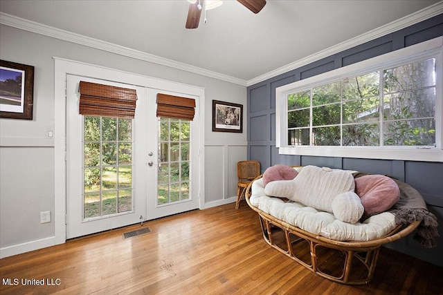 living area with french doors, light wood finished floors, ceiling fan, visible vents, and a decorative wall