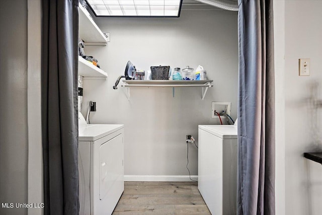 clothes washing area featuring independent washer and dryer, light wood-type flooring, baseboards, and laundry area