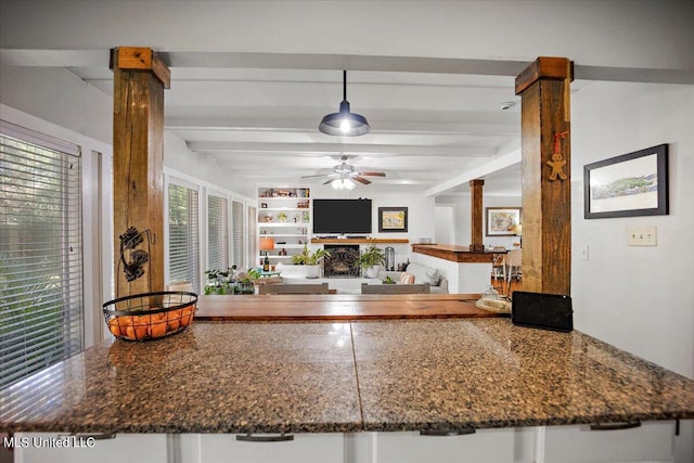 kitchen with ceiling fan, white cabinetry, dark stone counters, beam ceiling, and ornate columns
