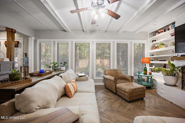 living area featuring beam ceiling, built in shelves, and a ceiling fan