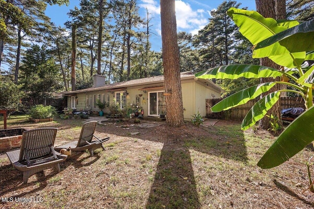 back of property with a chimney and fence