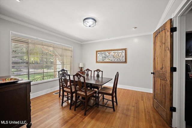 dining room with crown molding and light wood-type flooring