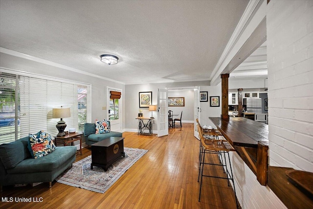 living room featuring ornamental molding, a textured ceiling, wood-type flooring, and a wealth of natural light