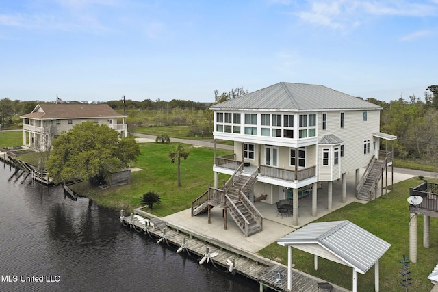 back of house featuring a yard, a water view, and a patio