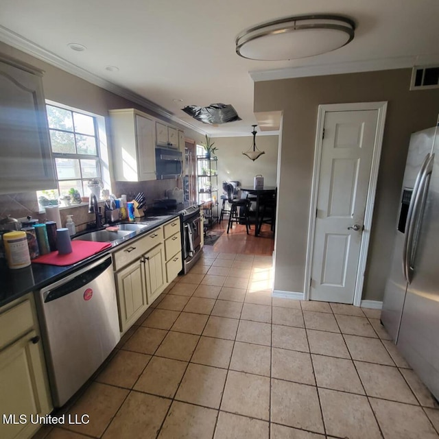 kitchen featuring appliances with stainless steel finishes, backsplash, sink, light tile patterned floors, and cream cabinetry