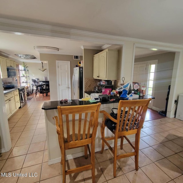 kitchen featuring decorative backsplash, appliances with stainless steel finishes, light tile patterned floors, and crown molding