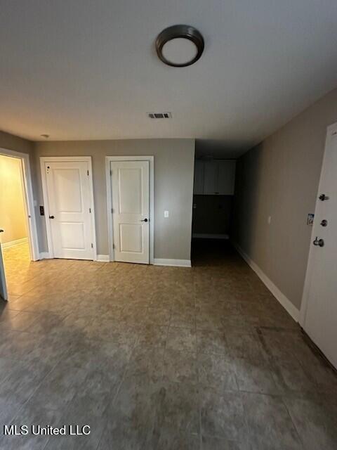 unfurnished living room with baseboards, visible vents, and tile patterned floors
