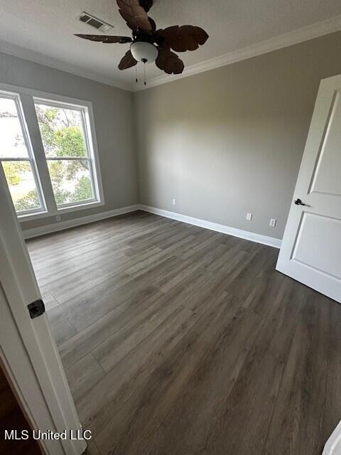 unfurnished room with baseboards, ornamental molding, dark wood-style floors, and visible vents