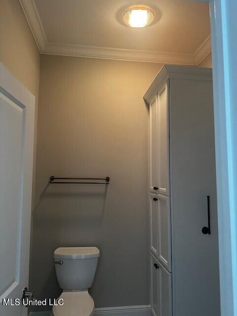 bathroom featuring toilet, baseboards, and ornamental molding