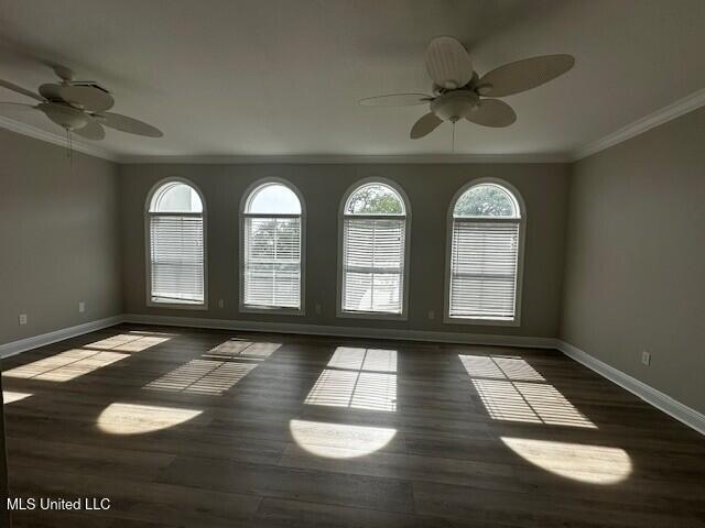 empty room with ceiling fan, ornamental molding, baseboards, and wood finished floors