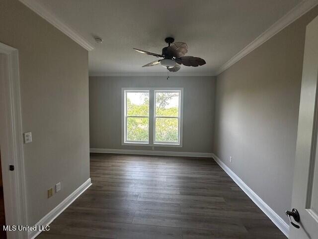 empty room featuring crown molding, baseboards, a ceiling fan, and dark wood finished floors