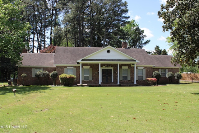 neoclassical home with a chimney, fence, and a front yard