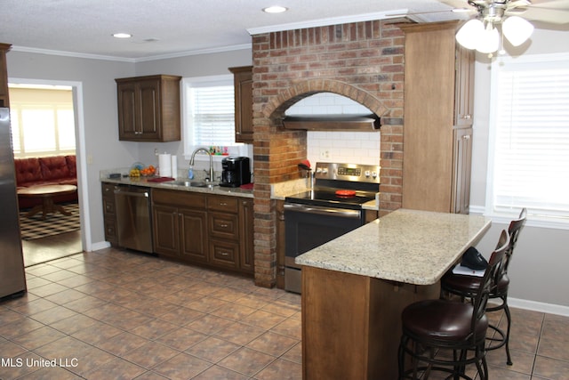 kitchen featuring a breakfast bar area, a sink, appliances with stainless steel finishes, and a healthy amount of sunlight