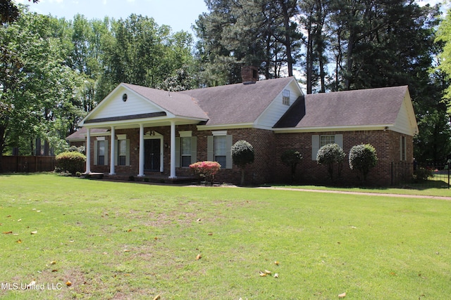 neoclassical / greek revival house with covered porch, a chimney, a front yard, and fence