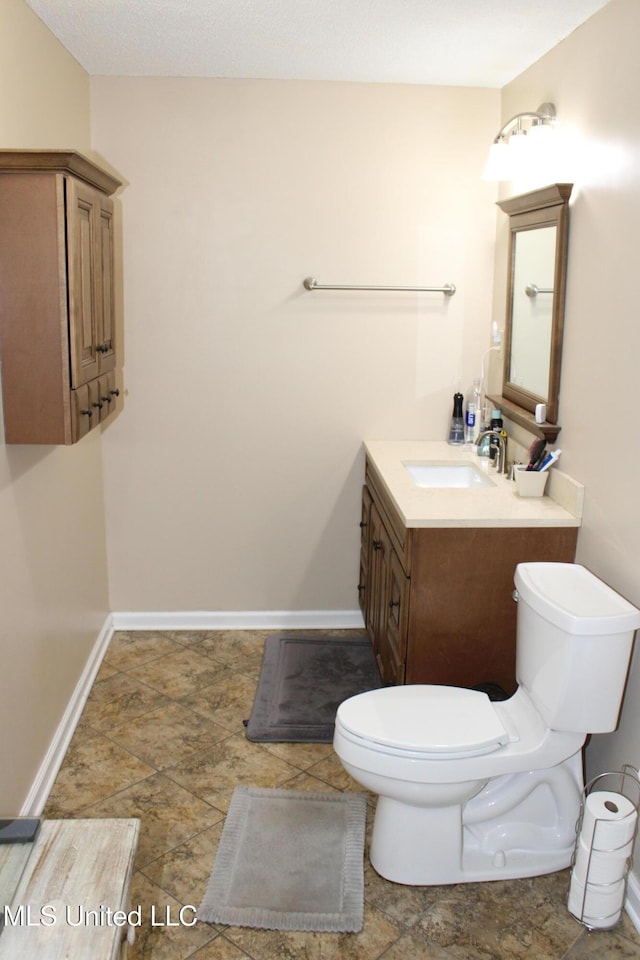bathroom featuring baseboards, toilet, and vanity