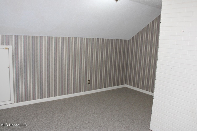 additional living space with vaulted ceiling, wallpapered walls, a textured ceiling, and carpet floors