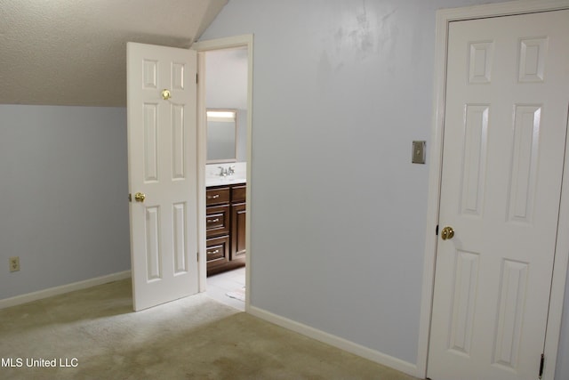 corridor with lofted ceiling, light carpet, baseboards, and a sink