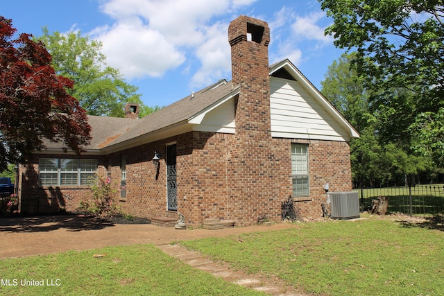 back of house featuring a chimney, central air condition unit, and a yard