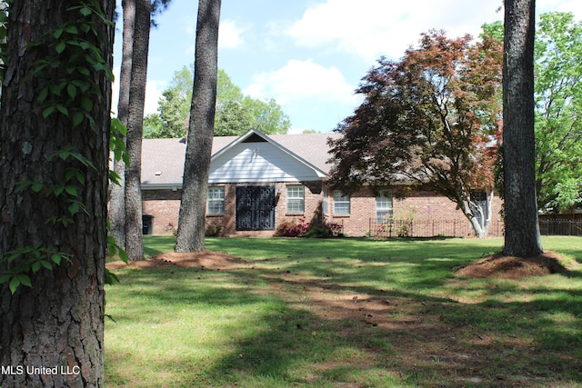 view of front of home featuring fence, a front lawn, and brick siding
