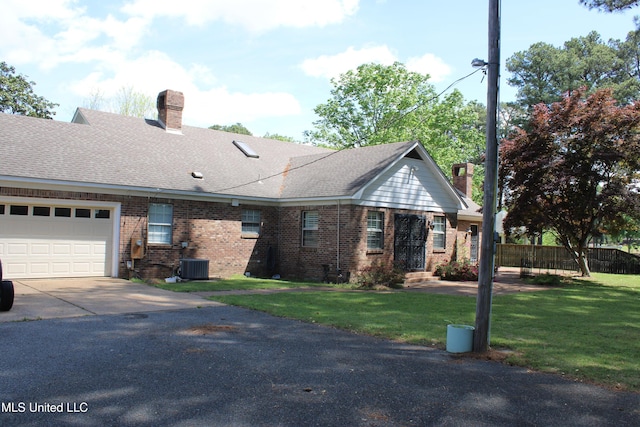 view of front of home featuring central air condition unit, a chimney, concrete driveway, brick siding, and a front yard