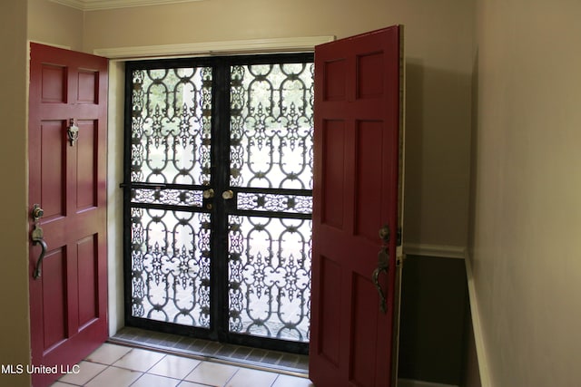 foyer with crown molding, a healthy amount of sunlight, tile patterned flooring, and baseboards
