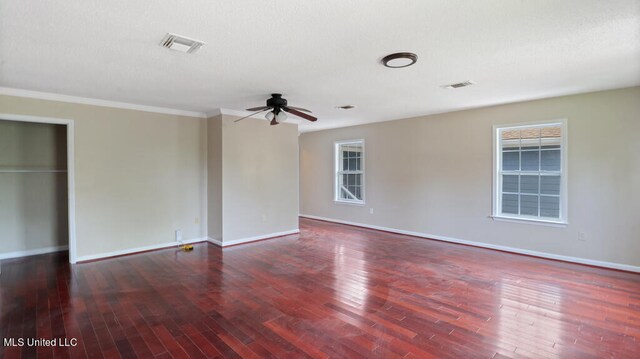 empty room with crown molding, plenty of natural light, dark wood-type flooring, and ceiling fan