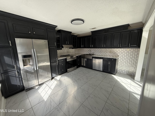 kitchen with dark cabinets, appliances with stainless steel finishes, a sink, and marble finish floor
