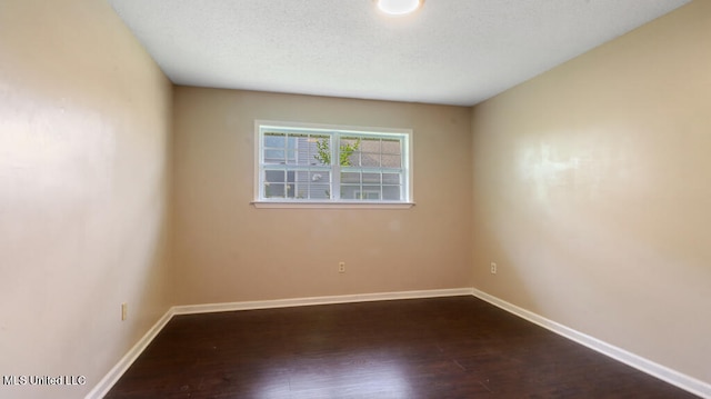 spare room with dark hardwood / wood-style floors and a textured ceiling