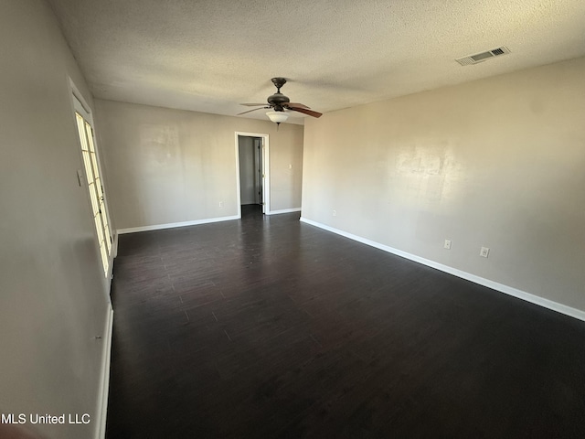 unfurnished room with a textured ceiling, dark wood finished floors, a ceiling fan, baseboards, and visible vents