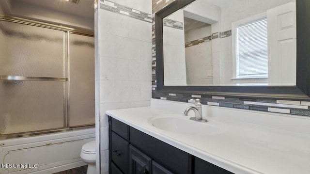 bathroom with plenty of natural light, toilet, combined bath / shower with glass door, and vanity