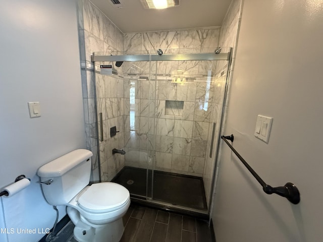 bathroom with a stall shower, wood finish floors, and toilet